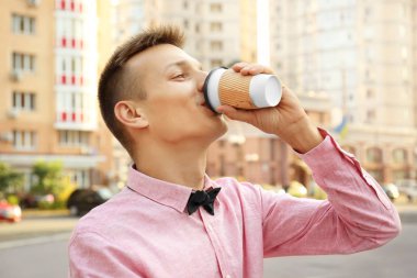 Pembe gömlekli sokakta kahve içme genç adam