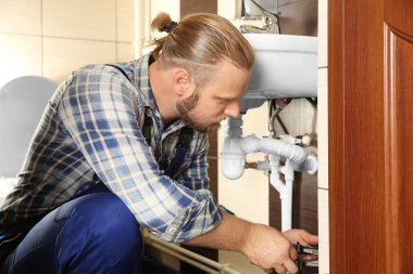 Handsome plumber repairing  clipart