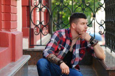 Genç dövmeli adam merdivenlerde, açık poz