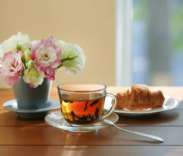 Kruvasan ve çiçekler ile çay — Stok fotoğraf