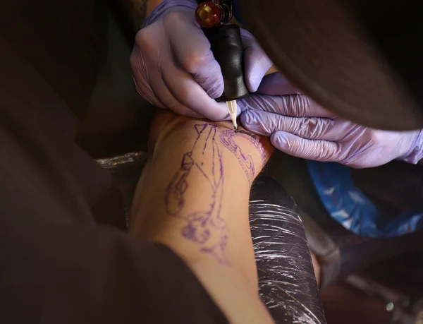 Professional artist making tattoo in salon, close up view