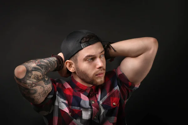 Joven hombre tatuado posando sobre fondo oscuro —  Fotos de Stock