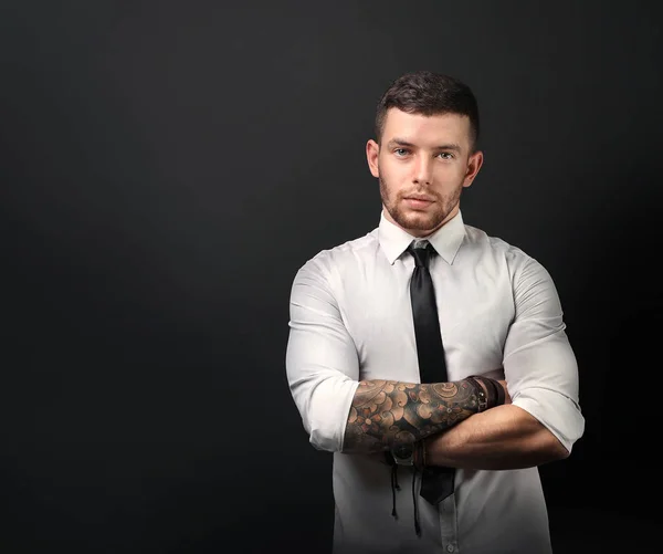 Young tattooed man posing on dark background — Stock Photo, Image