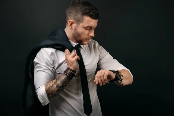 Jeune homme tatoué posant sur fond sombre — Photo