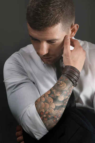 Молодой татуированный мужчина позирует на тёмном фоне — стоковое фото