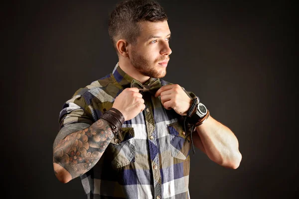 Joven hombre tatuado posando sobre fondo oscuro —  Fotos de Stock