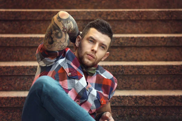 Jeune homme tatoué posant sur les escaliers, en plein air — Photo