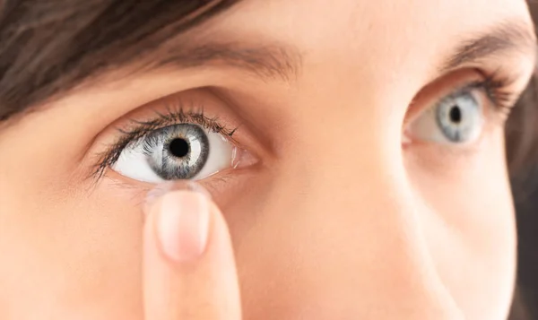 young woman putting contact lens