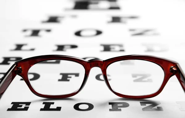 Glazen liggend op oog test-chart — Stockfoto