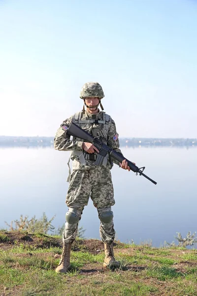 Soldier with rifle standing at military firing range near river