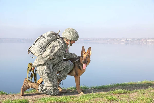 Soldier with german shepherd dog near river