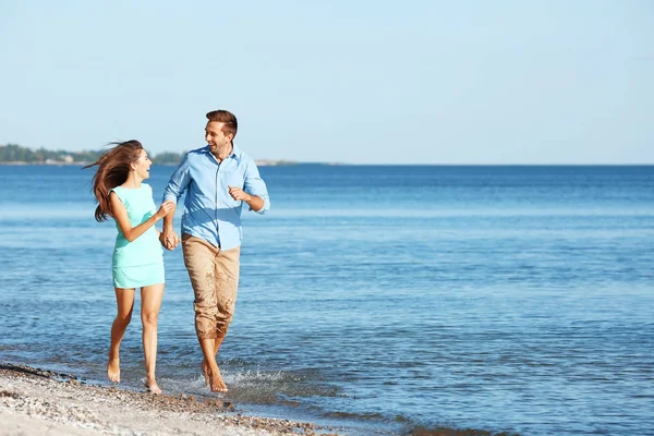 Par i kärlek promenader längs stranden — Stockfoto