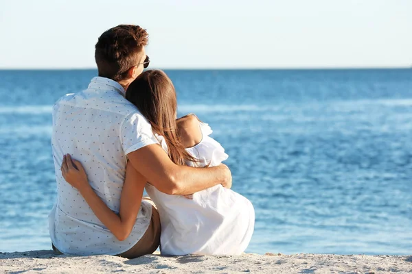 Feliz pareja sentada en la arena — Foto de Stock