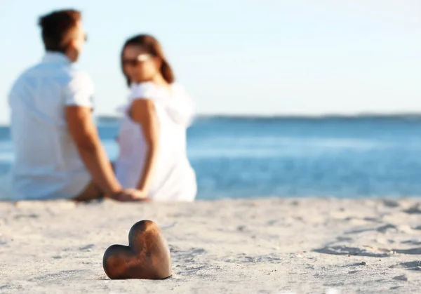 Dekoratives Herz auf Sand und Paar auf Hintergrund — Stockfoto