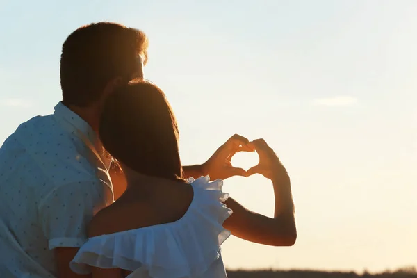 Jong koppel maken hart met hun handen op strand — Stockfoto