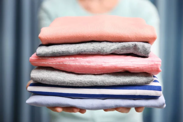 Woman holding folded clothes — Stock Photo, Image