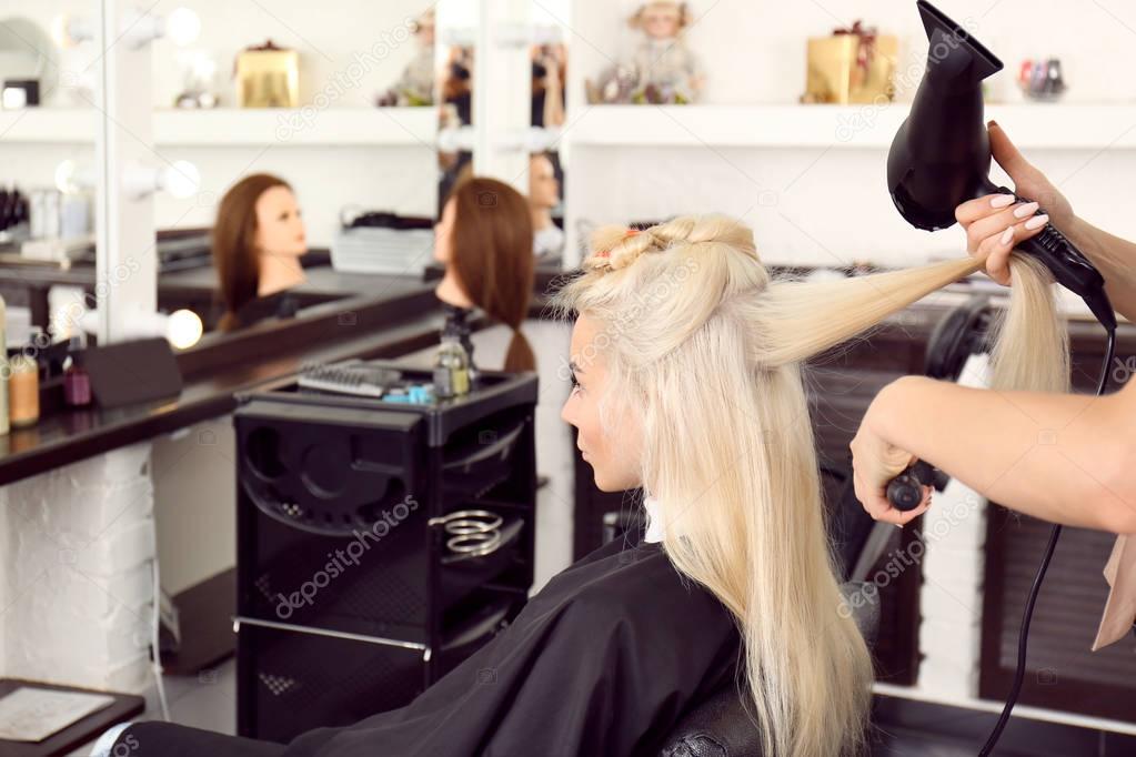 Hairdresser drying blonde's hair