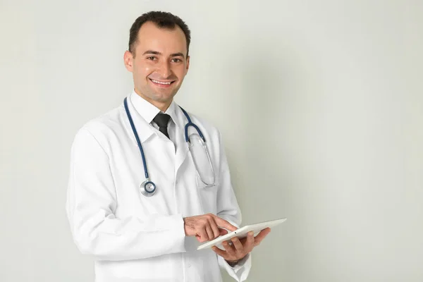 Doctor with tablet on color background — Stock Photo, Image