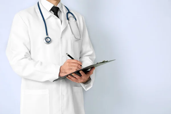 Arzt mit Klemmbrett auf farbigem Hintergrund — Stockfoto
