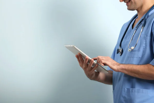 Arzt mit Tablet auf hellem Hintergrund — Stockfoto