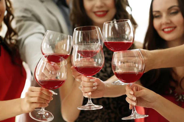 People toasting with glasses of red wine, closeup