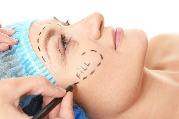 Mãos de cirurgião desenhando marcas no rosto feminino para operação plástica — Fotografia de Stock