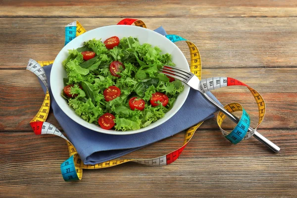 Fresh salad and measuring tape — Stock Photo, Image