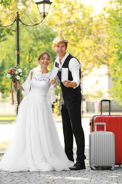 Novia y novio con maletas grandes caminando al aire libre —  Fotos de Stock
