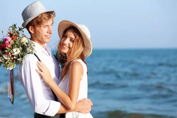 Счастливая пара с цветами на берегу моря — стоковое фото