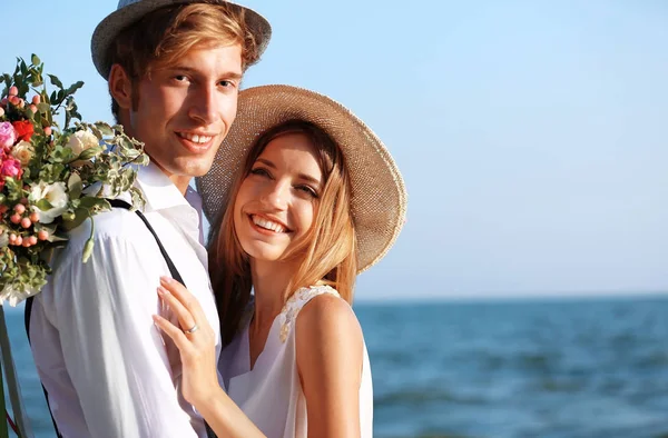 Happy couple with flowers on seashore — Stock Photo, Image