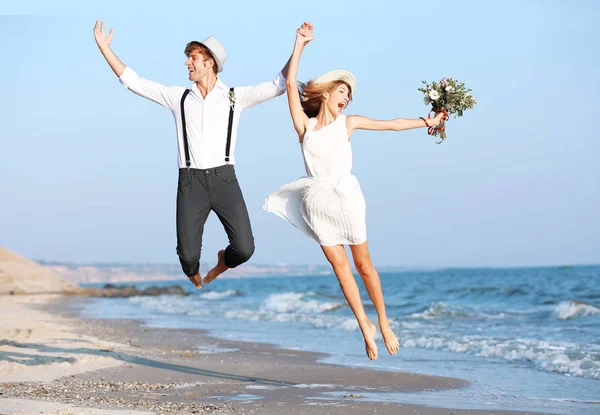 Счастливая пара, прыгающая на берегу моря — стоковое фото