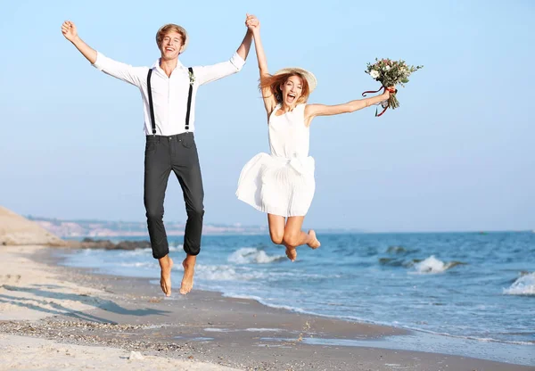 Happy couple jumping on seashore — Stock Photo, Image
