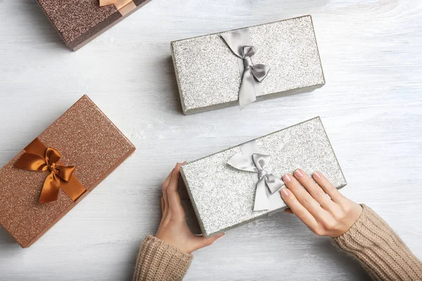 Handen van vrouw opening doos met Kerstmis presenteren op lichte houten achtergrond — Stockfoto