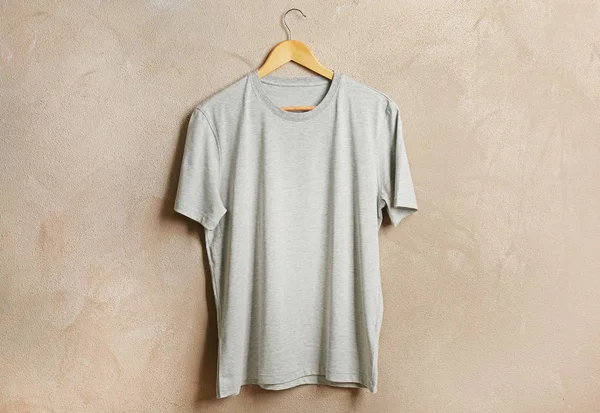 Gray t-shirt against grunge wall — Stock Photo, Image