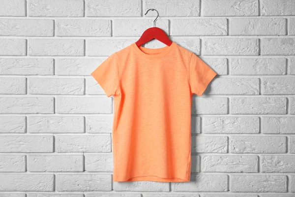 orange t-shirt against brickwall