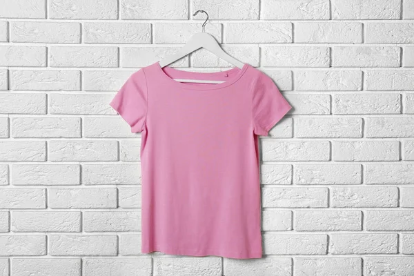 Розовая футболка против кирпичной стены — стоковое фото