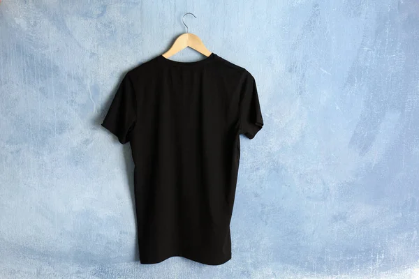 Black t-shirt against grunge wall — Stock Photo, Image