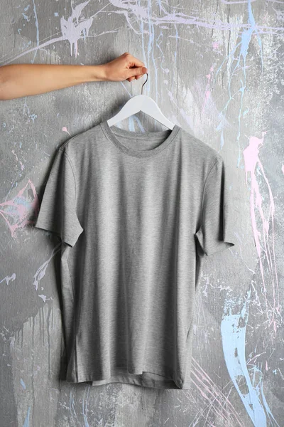 Gray t-shirt against grunge wall — Stock Photo, Image