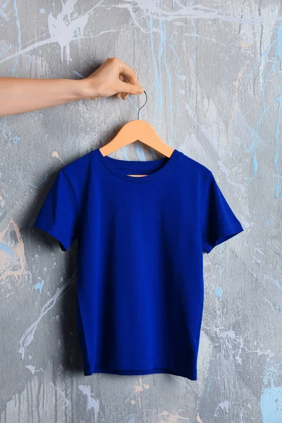 Blue t-shirt against grunge wall — Stock Photo, Image