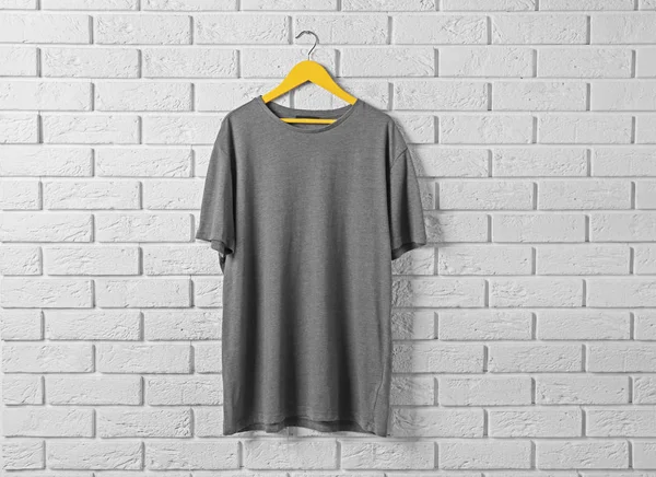 T-shirt gris contre le mur de briques — Photo