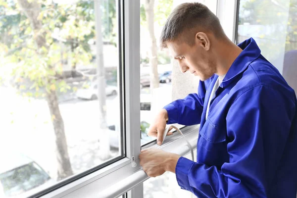 Arbeiter klebt Schaumstoffband auf Fenster — Stockfoto