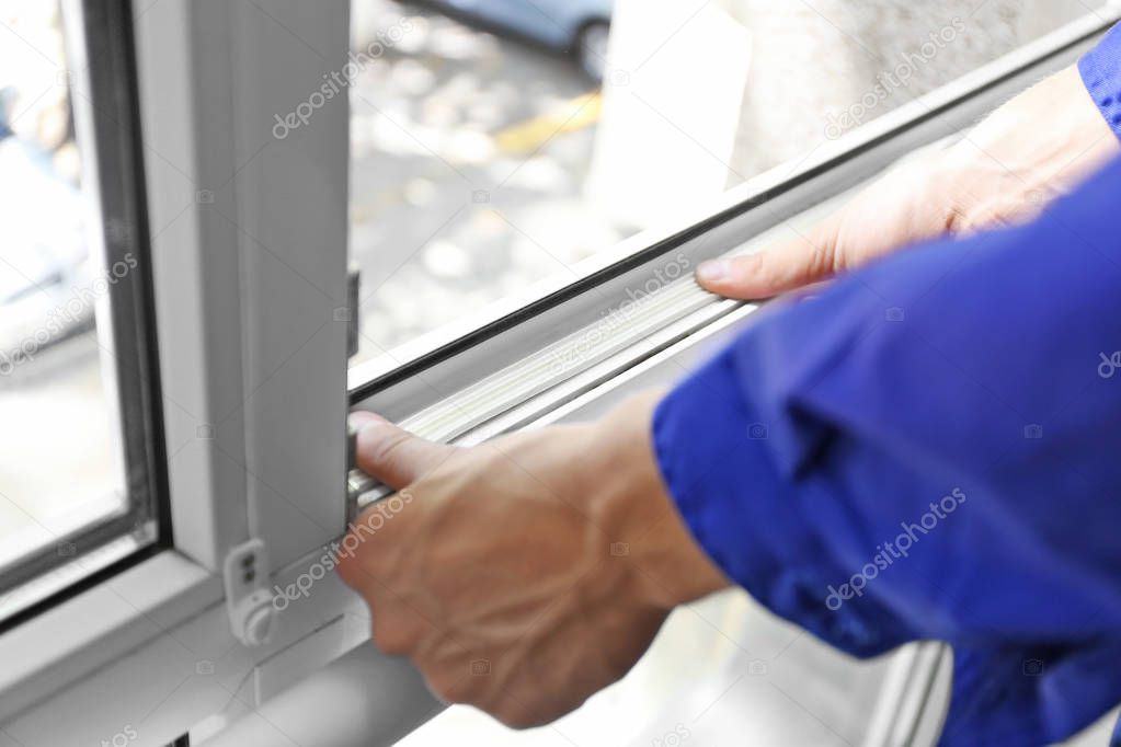 worker putting sealing foam tape on window