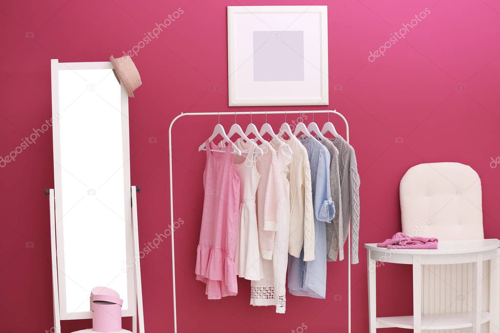 Fashionable clothes hanging on rack