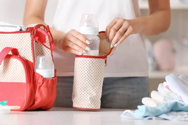 Mulher embalando sua bolsa com garrafa de criança — Fotografia de Stock