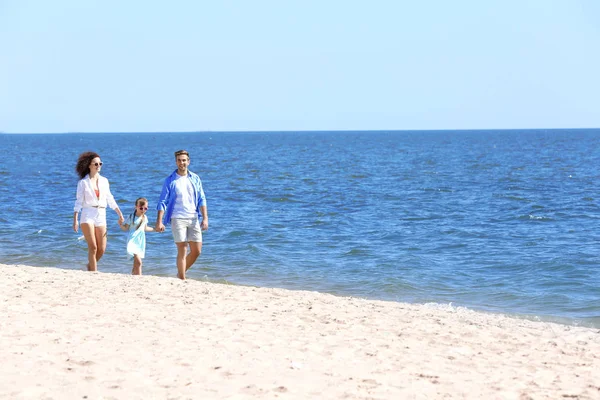 Concepto familiar. Padres con hija tomados de la mano y caminando en la orilla del mar — Foto de Stock