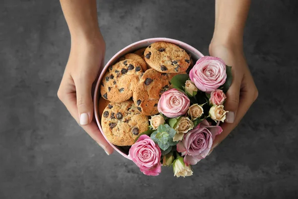 florist preparing box with flowers and cookies