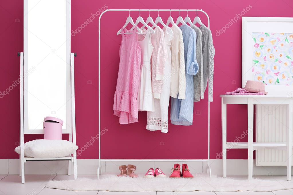 Fashionable clothes hanging on rack