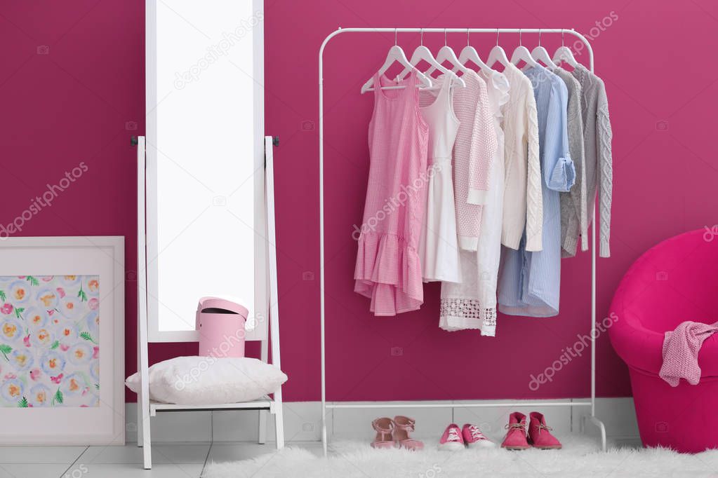 Fashionable clothes hanging on rack
