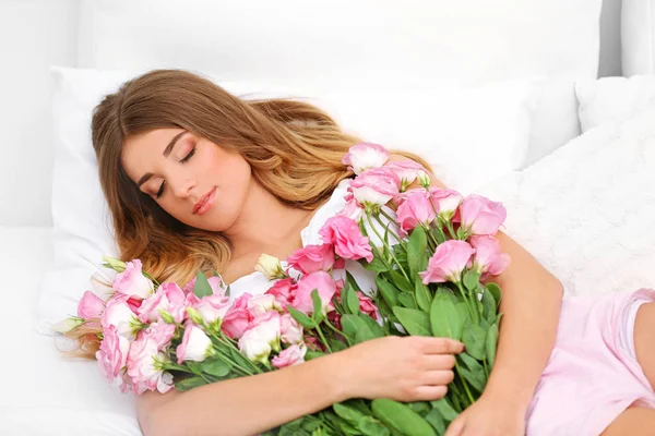 Pretty girl lying in bed with big bouquet — Stock Photo, Image