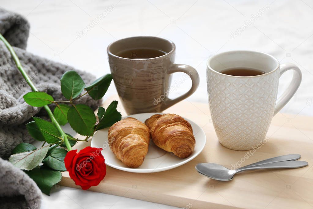 Cups of tea with croissants and rose 